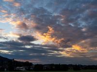 Dramatische angeleuchtete Wolken zwischen grauem Wolkenfeld über Aschau